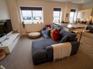 a living room with a blue couch and a kitchen at Pass the Keys Stunning 1 bedroom Penthouse in Nottm City Centre in Nottingham