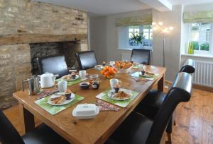 シップトン＝アンダー＝ウィッチウッドにあるGardeners Cottageのダイニングルームに木製テーブルと食べ物