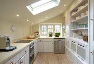 d'une cuisine avec des placards blancs et une lucarne. dans l'établissement Apple Cottage, à Snowshill