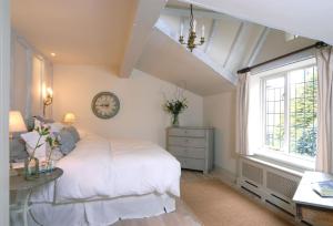 a bedroom with a white bed and a clock on the wall at Apple Cottage in Snowshill