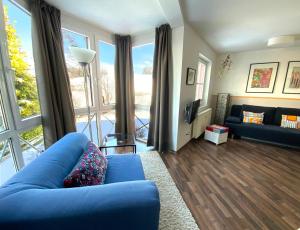 ein Wohnzimmer mit einem blauen Sofa und einem großen Fenster in der Unterkunft Apartment Heller am Hasselkopf in Braunlage
