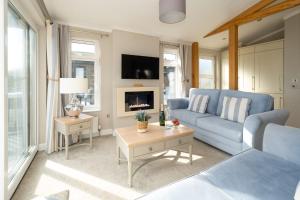 a living room with a blue couch and a tv at Hunky-Dory - Aldeburgh Coastal Cottages in Sizewell