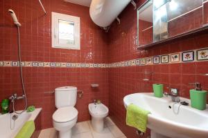 W wyłożonej czerwonymi kafelkami łazience znajduje się toaleta i umywalka. w obiekcie Villa Beatrice by Villa Plus w mieście Binibeca +12 zdjęć