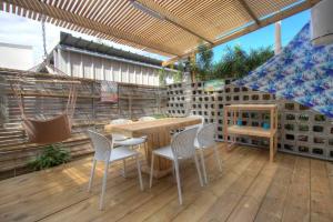 eine Terrasse mit einem Tisch und Stühlen auf einem Holzboden in der Unterkunft Kaz Lotis - à 50m de la plage Roches Noires in Saint-Gilles-les-Bains