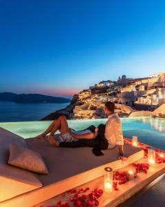 two people sitting on a bench overlooking the ocean at Echoes Luxury Suites in Oia