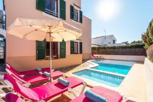 Cette villa dispose d'une piscine avec des chaises roses et un parasol. dans l'établissement Villa Matias Maria by Villa Plus, à Cala en Blanes