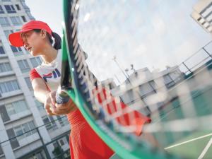 una mujer sosteniendo una raqueta de tenis en una cancha en HARRIS Suites fx Sudirman, en Yakarta