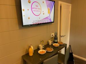 a television on a wall with a table with food at P56 - Studio Pod with Hot Tub in Bethesda