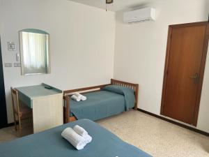 ein Zimmer mit zwei Betten, einem Waschbecken und einem Spiegel in der Unterkunft Ubika Hotel in Porto San Giorgio