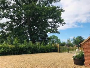 a driveway with a fence and a tree at The Lodge in North Bradley