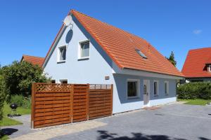 a house with an orange roof and a wooden fence at Haus Wiekend - Fewo Strandkrabbe in Wiek auf Rügen 