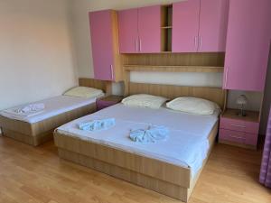two beds in a room with pink cabinets at Apartmani Kacola in Tučepi