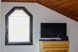 a flat screen tv sitting on a dresser next to a window at Къща за гости,,Вила Росица,, in Shabla