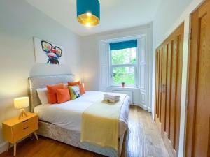 ein Schlafzimmer mit einem Bett mit orangefarbenen Kissen und einem Fenster in der Unterkunft Desirable 2 Bed Apt Near Edinburgh Castle in Edinburgh