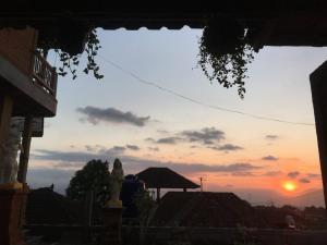 Un tramonto su una città con una statua in primo piano di Meme Surung Guesthouse a Munduk