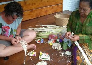 dos mujeres sentadas en el suelo haciendo flores en Meme Surung Guesthouse, en Munduk