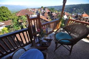 a balcony with two chairs and a table with a view at Meme Surung Guesthouse in Munduk