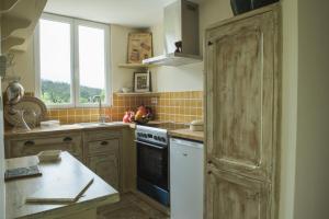 eine Küche mit einem Herd, einem Waschbecken und einem Fenster in der Unterkunft Chapel Cottage in La Bachellerie + 11 Fotos