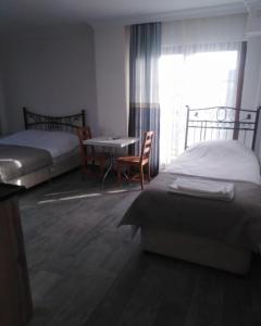 a bedroom with two beds and a table and a window at Nur Konak daire 3 in Çanakkale