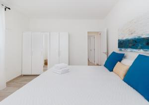 ein Schlafzimmer mit einem großen weißen Bett mit blauen Akzenten in der Unterkunft Moderno apartamento urbano en barrio histórico 2ºI in Santa Cruz de Tenerife