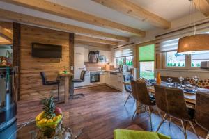 a kitchen and living room with wooden walls and a dining room at Chalets AurAlpin in Kleinarl