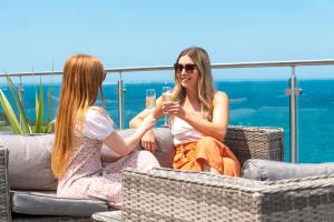 two women sitting in chairs with a glass of wine at Fistral Beach Hotel and Spa - Adults Only in Newquay