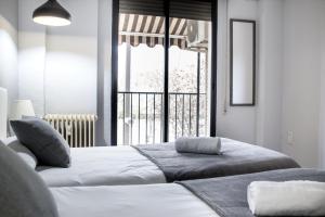two beds in a room with a large window at City Center in Granada