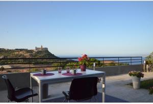 a table on a balcony with a view of the ocean at La Casa del Riccio in Tindari