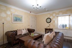 a living room with leather couches and a table at The Old Schoolhouse of Warren Lodge Boutique Cottages in Dromod