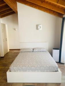 białe łóżko w sypialni z drewnianym sufitem w obiekcie Casa Cleopatra w Bergamo