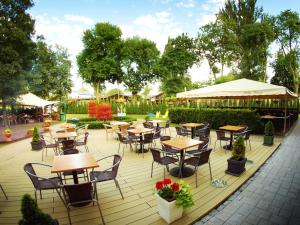 un patio al aire libre con mesas, sillas y árboles en Willa Nowa en Ciechocinek