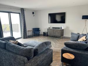 a living room with two couches and a flat screen tv at Machrie View in Port Ellen