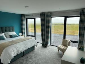 a bedroom with a large bed and a large window at Machrie View in Port Ellen