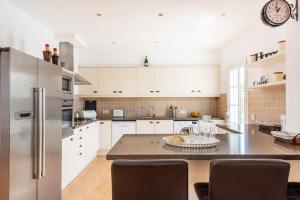 a kitchen with white cabinets and a stainless steel refrigerator at Villa Sidanya by Villa Plus in Cala en Porter