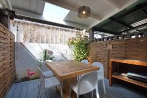 patio z drewnianym stołem i białymi krzesłami w obiekcie Kaz Nomia - à 50m de la plage Roches Noires w mieście Saint-Gilles les Bains
