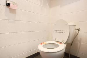 a bathroom with a toilet with a sign on the lid at Kaz Nomia - à 50m de la plage Roches Noires in Saint-Gilles les Bains