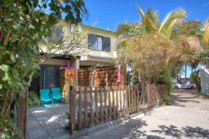 a house with two blue chairs in front of a fence at Kaz Nomia - à 50m de la plage Roches Noires in Saint-Gilles les Bains