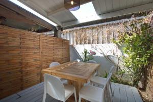 a wooden table and white chairs on a patio at Kaz Nomia - à 50m de la plage Roches Noires in Saint-Gilles les Bains +18 photos