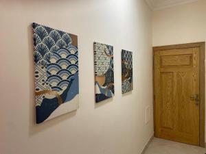 three paintings hanging on a wall next to a door at Beautiful Flat By The Beach Salalah in Salalah