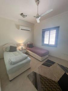 a bedroom with two beds and a ceiling fan at Beautiful Flat By The Beach Salalah in Salalah