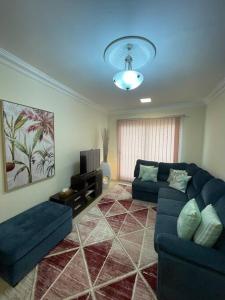 a living room with a blue couch and a tv at Beautiful Flat By The Beach Salalah in Salalah