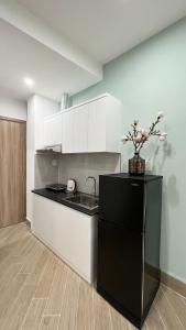 una cucina con frigorifero nero e armadietti bianchi di MIDMOST C22 Apartment a Can Tho