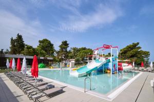 a beach area with a pool, chairs and umbrellas at Hotel Sipar Plava Laguna in Umag