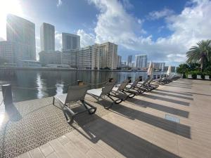 a row of chairs sitting next to a body of water at Upscale Beach Apartment, Style, Views & Complete Kitchen -28A in Hallandale Beach