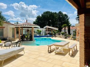 a patio with a table and a swimming pool at Le Mas des Mathes, Chambres d'hôtes, Studios in Les Mathes