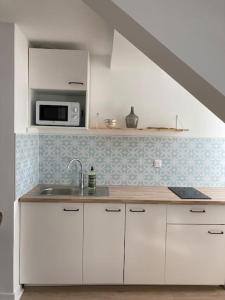 Biała kuchnia ze zlewem i kuchenką mikrofalową w obiekcie Studio neuf Pont-rousseau Rezé w mieście Rezé