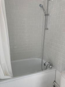 a white bath tub with a shower in a bathroom at Studio neuf Pont-rousseau Rezé in Rezé
