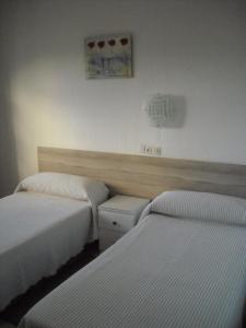 a hotel room with two beds and a television at Hostal Flor Blanco in Torremolinos