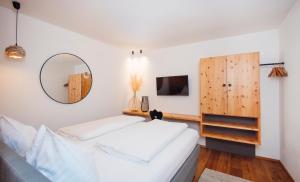 a bedroom with a large white bed and a mirror at Hotel Gasthof Hirschentenne in Stams