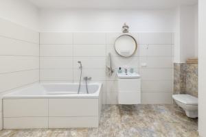 a white bathroom with a tub and a toilet at Open Lakes Apartamenty Giżycko in Giżycko